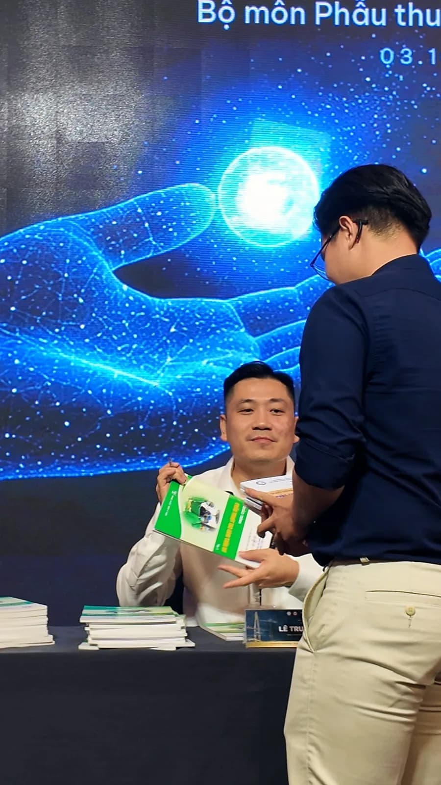 Dr. Kien handing a textbook to a colleague
