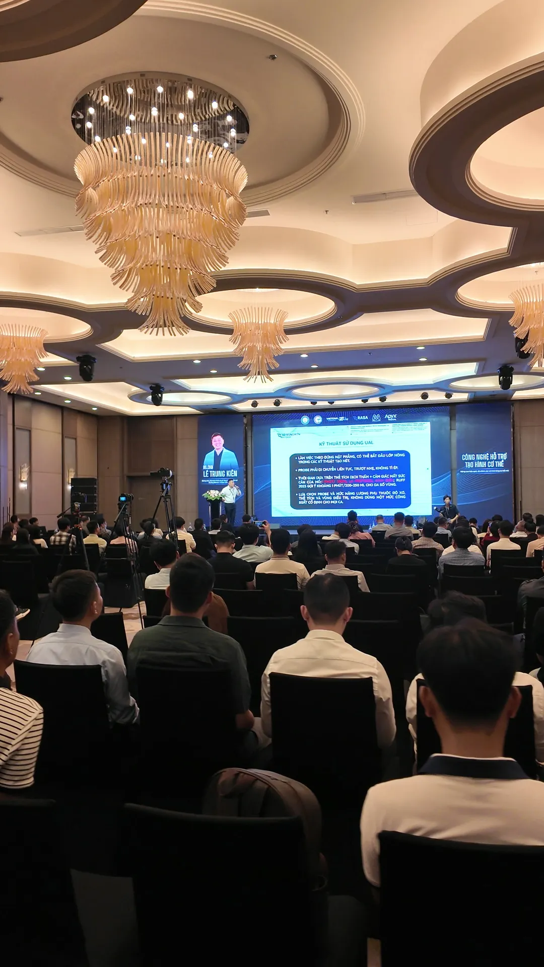 The lecture on liposuction technologies seen from the back of the hall